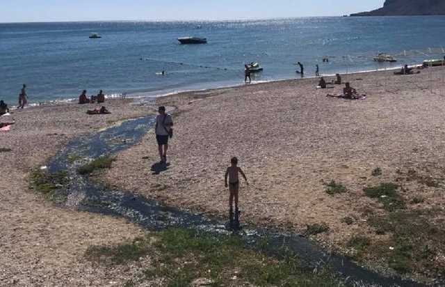 В Крыму люди отдыхают на пляже возле сточной канавы