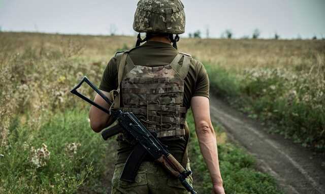 Український воїн кидає гранату в сховок окупантів під пошкодженим танком