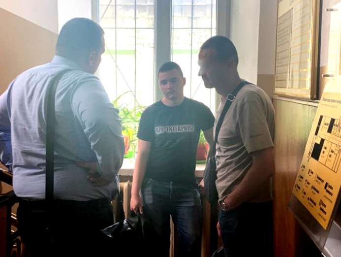 Подозреваемый (в центре) перед началом суда