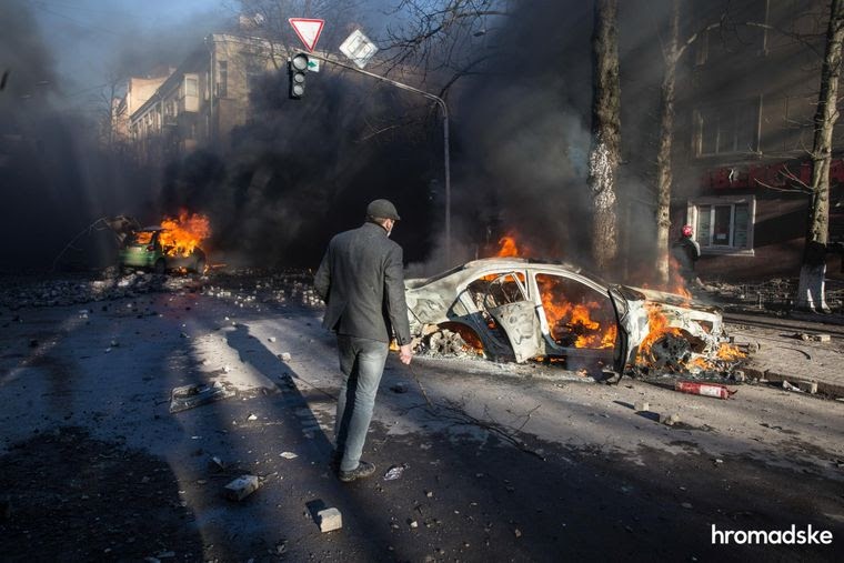Мужчина смотрит на автомобили, сожженные во время столкновений между протестующими и силовиками на пересечении улиц Институтской и Шелковичной в Киеве, 18 февраля 2014 года