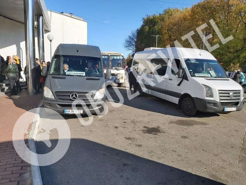 Возле здания стоит более 10 похоронных автобусов.