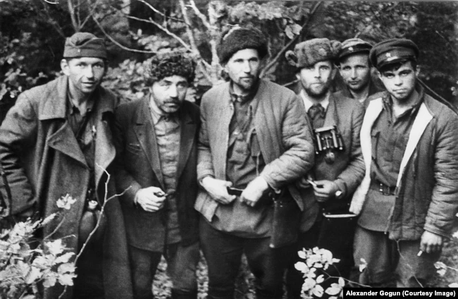 Группа партизан ковпаковского соединения. Слева направо: Василий Войцехович (начштаба Сумского соединения с августа 1943 г.), Михаил Павловский (завхоз соединения), Григорий Базима (начштаба соединения до августа 1943 г.), Ф. Горкунов (начштаба Шалыгинского отряда Сумского соединения), К. Руднев (брат комиссара), Радий Руднев (сын комиссара)
