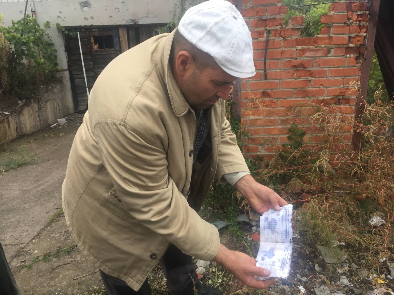 Сергій Ус демонструє покинуті армійські медичні книжки біля будинку, де розташовувалася медична частина російських військових. Фото Дмитро Дурнєв/Spektr.press