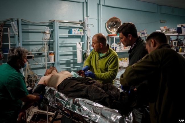 Военные врачи оказывают первую помощь раненому украинскому воину близ Бахумута в Донецкой области. Май 2023 года