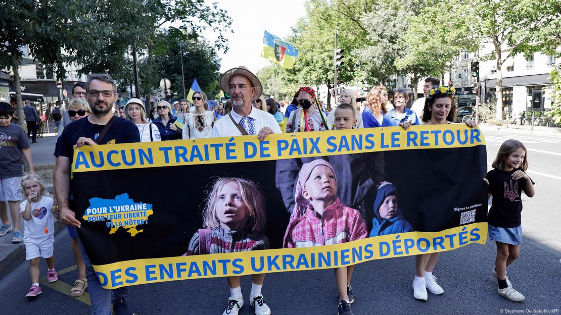 Учасники демонстрації на підтримку України в Парижі несуть плакат із закликом повернути депортованих дітей з РФ, 24 серпня 2025 року dqxikeidqxitkant